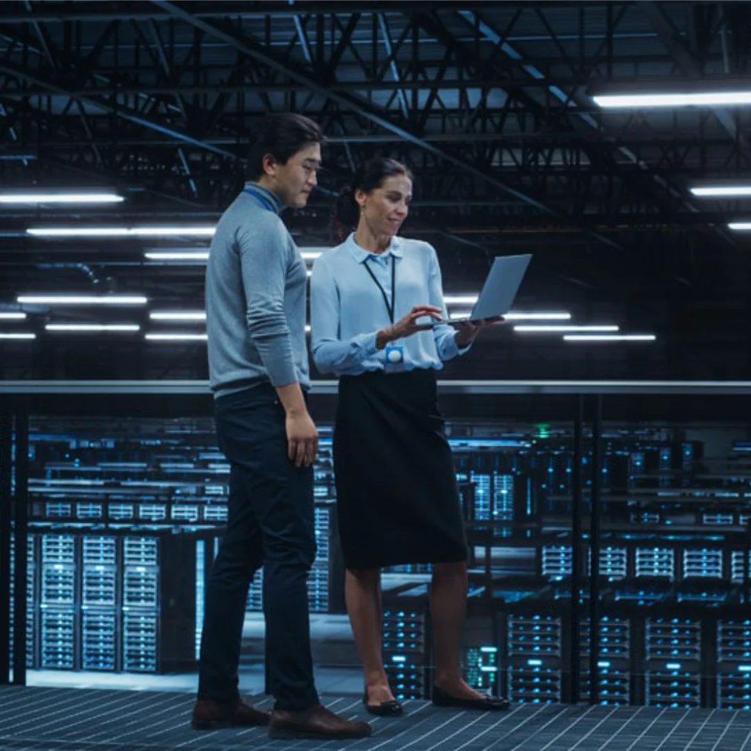 Man and woman standing in data center room checking security footage