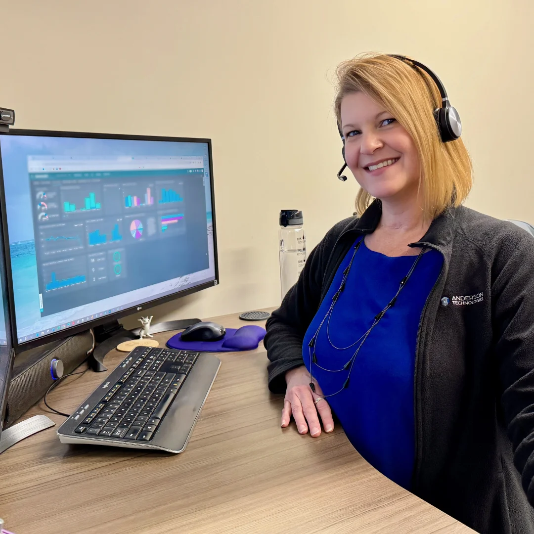 Smiling member of Anderson wearing a headset sitting at a desk