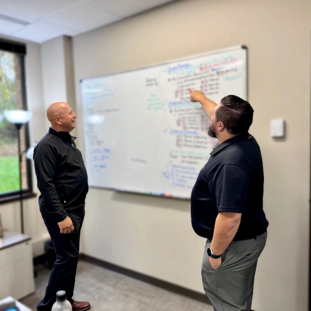 Two Anderson staff standing by white board discussing upcoming projects