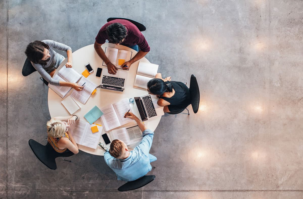 5 colleagues around circle table working from above